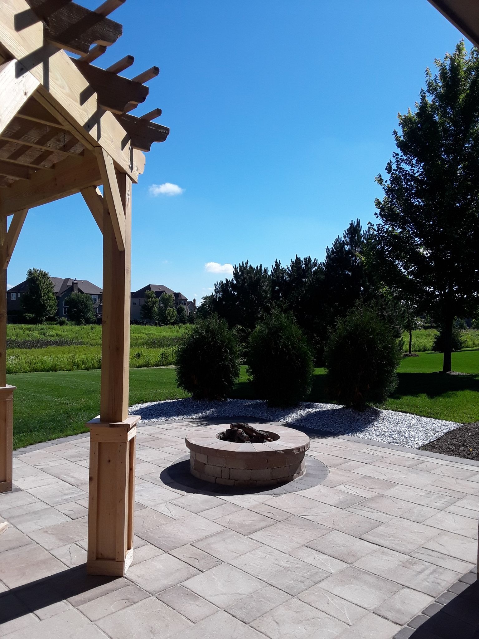 Paver patio, fire pit, and pergola overlooking a Barrington backyard.